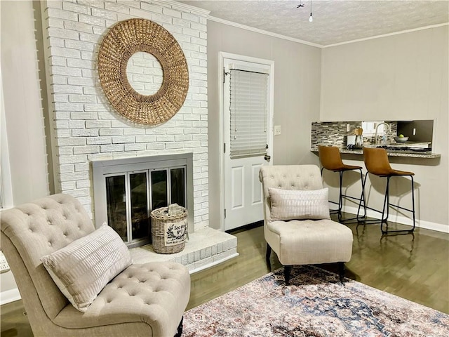 living area featuring a textured ceiling, a fireplace, ornamental molding, and dark hardwood / wood-style floors