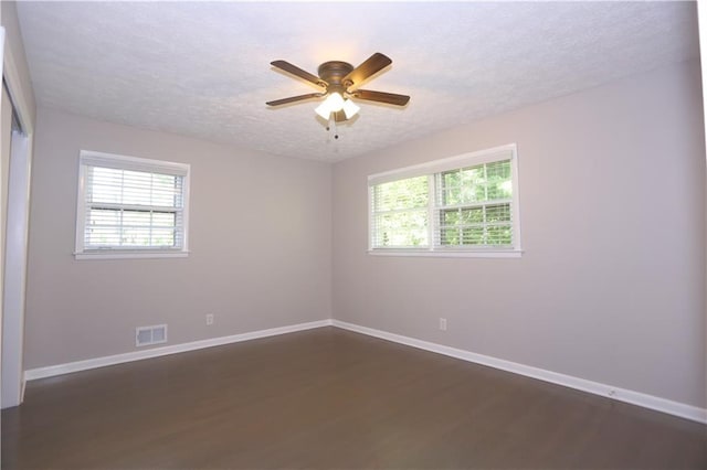 empty room with a textured ceiling, dark hardwood / wood-style floors, and ceiling fan