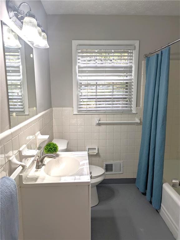 full bathroom with shower / bath combo with shower curtain, vanity, toilet, and tile walls