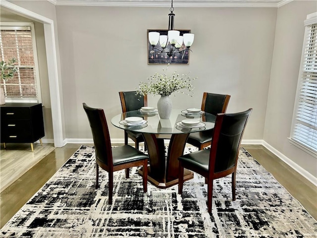 dining area with dark hardwood / wood-style floors, crown molding, and an inviting chandelier