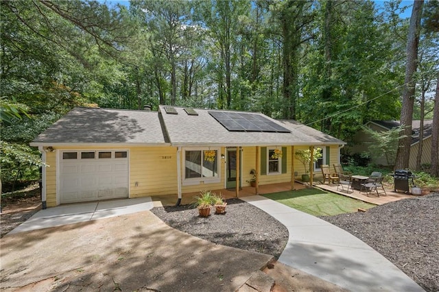 view of front of home with a fire pit, solar panels, a patio area, and a garage