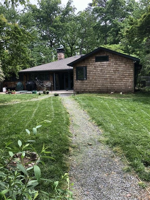 view of front of home with driveway, a chimney, and a front lawn