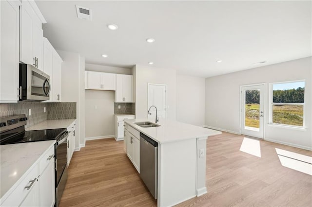 kitchen with appliances with stainless steel finishes, a kitchen island with sink, sink, and light wood-type flooring