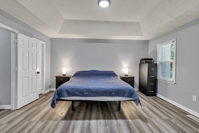3910 Meeting St, Duluth, GA 30096 - bedroom featuring a tray ceiling, light wood-style floors, baseboards, and a textured ceiling