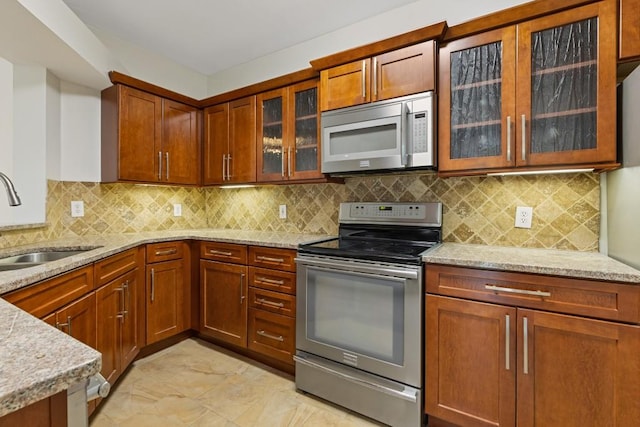 3334 Peachtree Rd NE Unit 101, Atlanta, GA 30326 - kitchen with stainless steel appliances, a sink, light stone counters, decorative backsplash, and light marble finish flooring