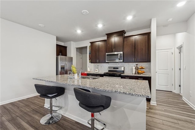 kitchen with a breakfast bar, appliances with stainless steel finishes, a kitchen island with sink, and sink