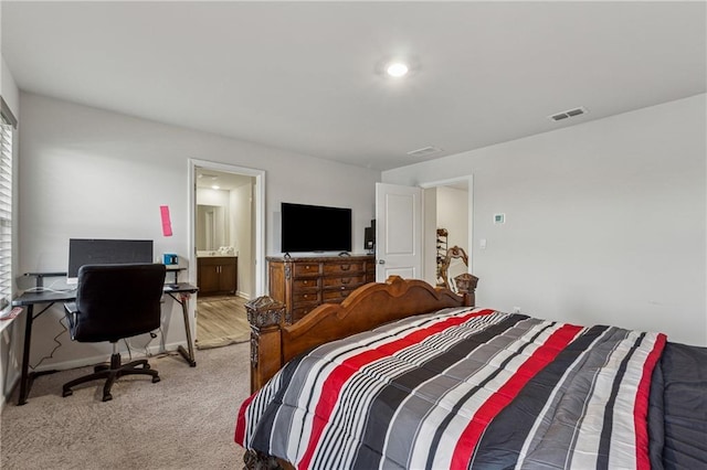 bedroom featuring ensuite bathroom and light colored carpet