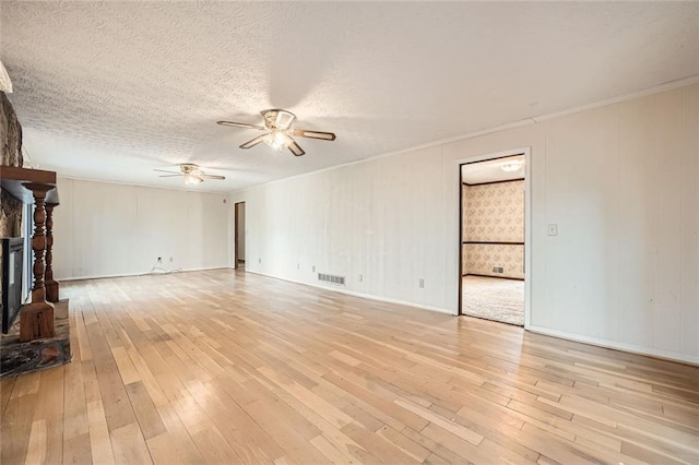 unfurnished living room featuring ceiling fan, a textured ceiling, a fireplace, and light hardwood / wood-style flooring