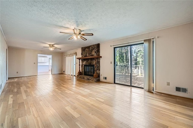 unfurnished living room featuring ceiling fan, light wood-type flooring, a fireplace, and a textured ceiling