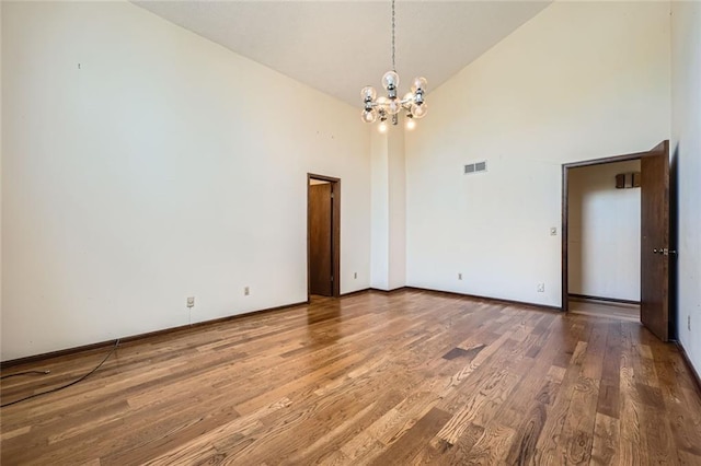 unfurnished room with wood-type flooring, a chandelier, and high vaulted ceiling