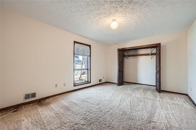 unfurnished bedroom featuring light colored carpet, a textured ceiling, and a closet