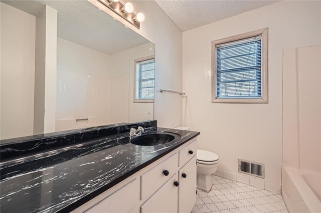 bathroom with a healthy amount of sunlight, toilet, a textured ceiling, and vanity