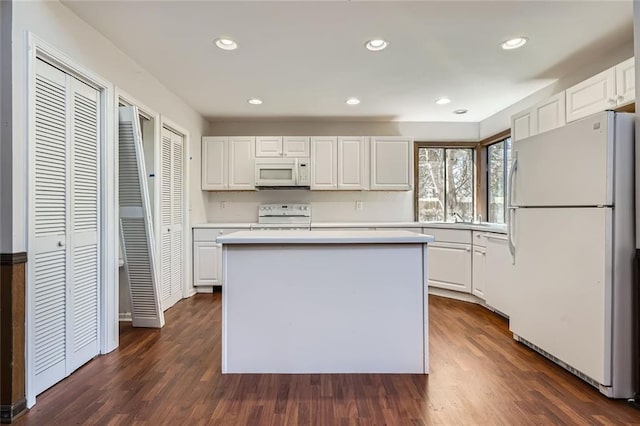 kitchen with white cabinetry, white appliances, a center island, and dark wood-type flooring