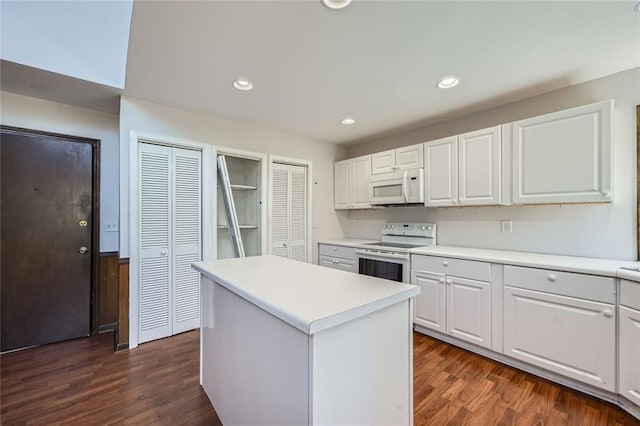 kitchen featuring dark hardwood / wood-style flooring, white cabinetry, a kitchen island, and white appliances