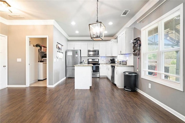 kitchen with stainless steel appliances, washer / clothes dryer, a chandelier, ornamental molding, and a center island