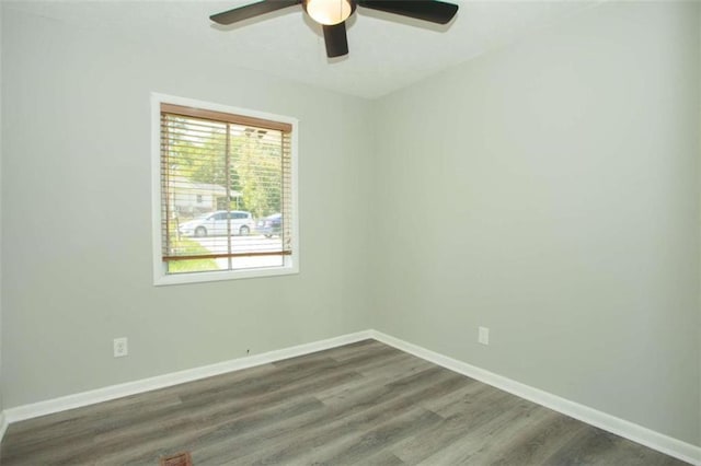 empty room with dark wood-type flooring, baseboards, and ceiling fan