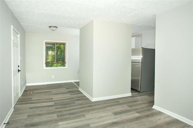 hall featuring a textured ceiling, baseboards, and wood finished floors