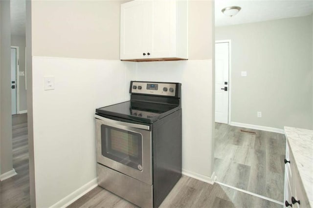 kitchen with electric range, wood finished floors, baseboards, and white cabinets