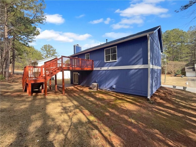 rear view of property with a deck, a chimney, stairs, and a lawn