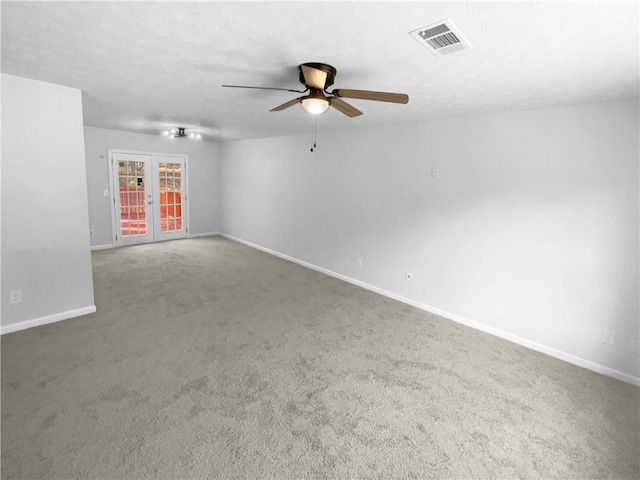 empty room featuring a textured ceiling, carpet flooring, visible vents, baseboards, and french doors