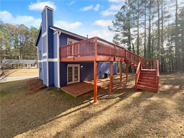 view of play area featuring a yard, stairway, a deck, and french doors