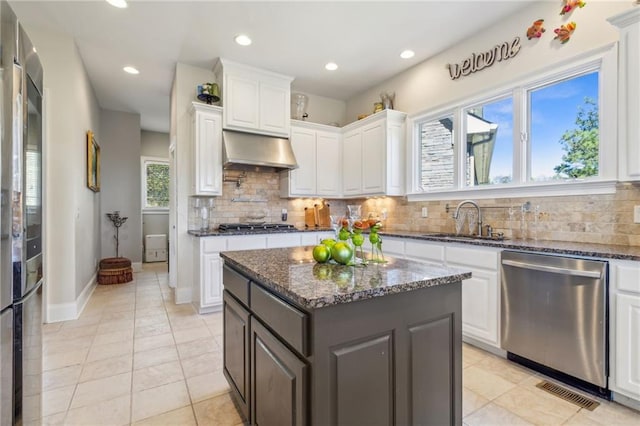 kitchen with stainless steel appliances, white cabinetry, exhaust hood, sink, and a center island