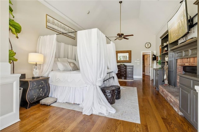 bedroom with a brick fireplace, high vaulted ceiling, dark hardwood / wood-style floors, and ceiling fan