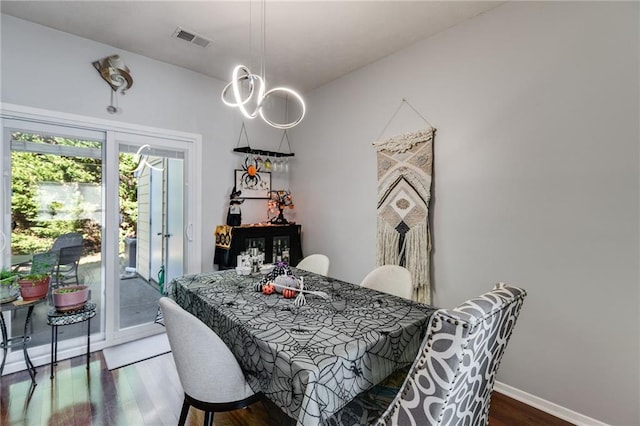 dining space featuring baseboards, wood finished floors, and visible vents