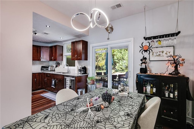 dining space with an inviting chandelier, a toaster, wood finished floors, and visible vents