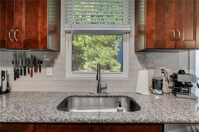 kitchen featuring light stone counters, a sink, and tasteful backsplash