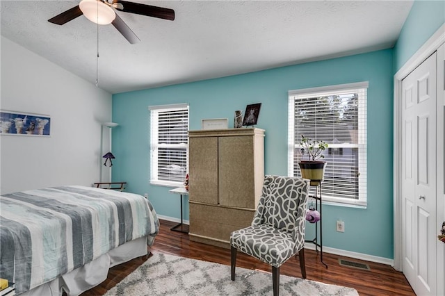 bedroom with visible vents, baseboards, wood finished floors, and a closet
