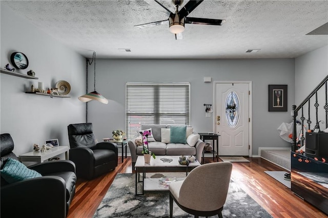 living area featuring visible vents, a ceiling fan, stairs, and wood finished floors