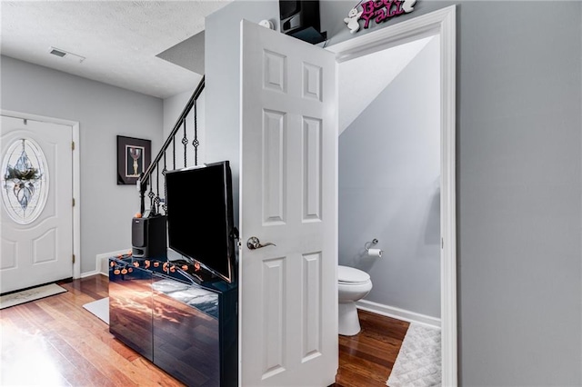 entrance foyer featuring baseboards, a textured ceiling, wood finished floors, and visible vents