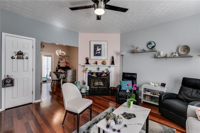 living room with a textured ceiling, wood finished floors, and ceiling fan with notable chandelier