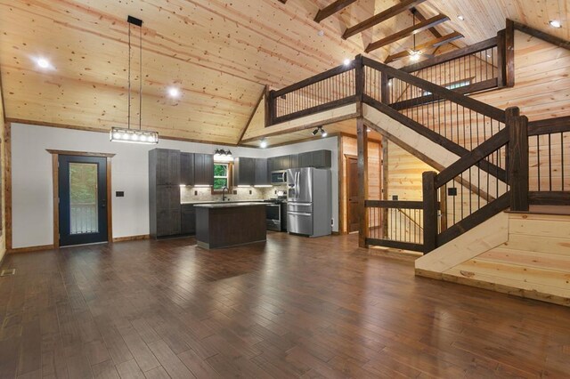 kitchen featuring dark wood-type flooring, appliances with stainless steel finishes, decorative light fixtures, backsplash, and high vaulted ceiling