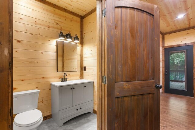 bathroom featuring oversized vanity, wood-type flooring, wood walls, toilet, and wooden ceiling