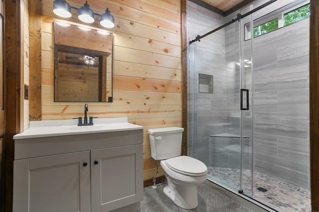 bathroom featuring wood walls, toilet, and vanity with extensive cabinet space