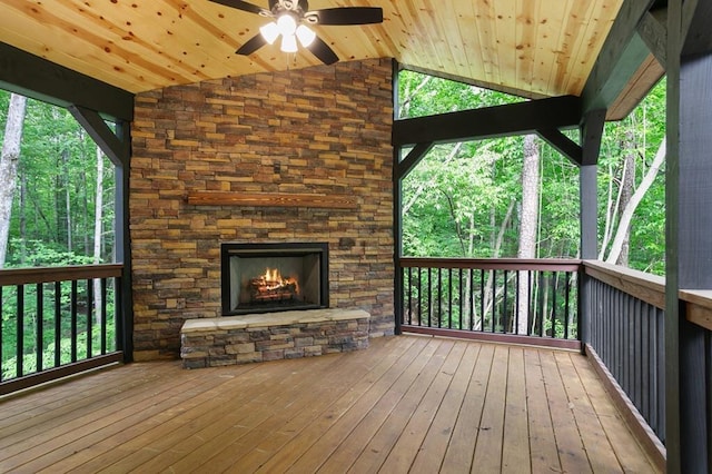 deck featuring a stone fireplace and ceiling fan