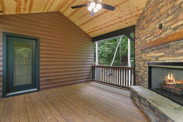 wooden deck featuring an outdoor stone fireplace and ceiling fan