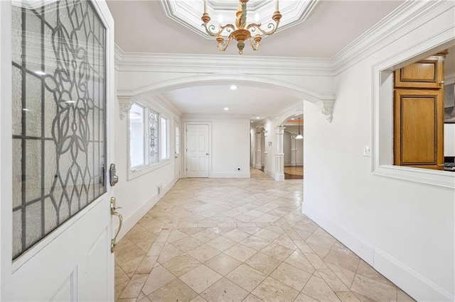 foyer with crown molding, decorative columns, and a chandelier