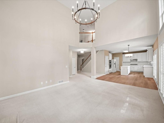 740 Orchard Ct, Atlanta, GA 30328 - unfurnished living room with a chandelier, a towering ceiling, light carpet, and stairs