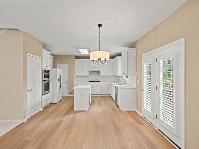 740 Orchard Ct, Atlanta, GA 30328 - kitchen with stainless steel appliances, light countertops, a chandelier, a kitchen island, and light wood-style flooring