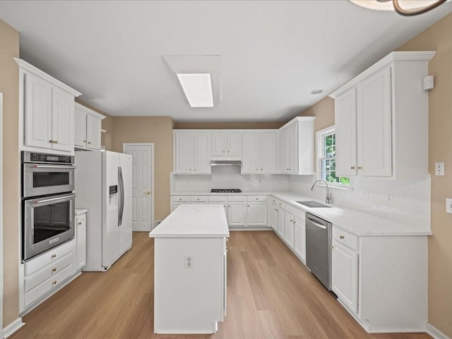 740 Orchard Ct, Atlanta, GA 30328 - kitchen featuring appliances with stainless steel finishes, light wood-style floors, a center island, and white cabinetry