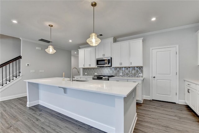 6270 Bracken Brown Dr, Alpharetta, GA 30004 - kitchen with stainless steel microwave, ornamental molding, backsplash, light wood-type flooring, and a kitchen island with sink