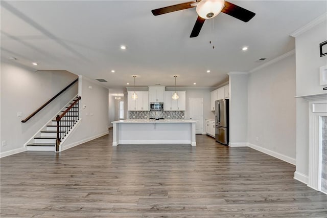 6270 Bracken Brown Dr, Alpharetta, GA 30004 - unfurnished living room with recessed lighting, crown molding, stairs, wood finished floors, and a ceiling fan