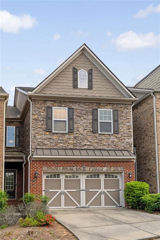 view of front of house with a garage, driveway, brick siding, and stone siding