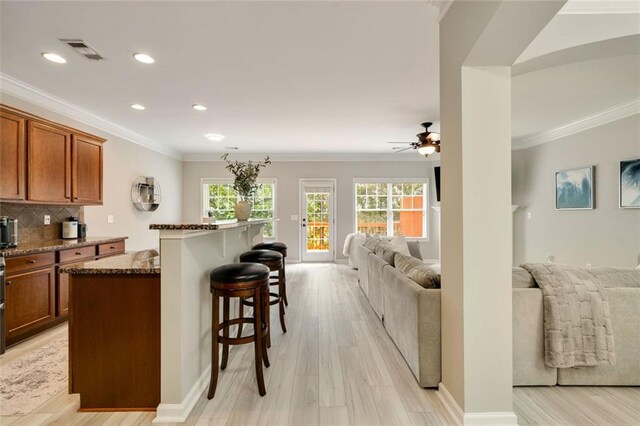 kitchen featuring a healthy amount of sunlight, ceiling fan, a breakfast bar area, brown cabinets, and open floor plan
