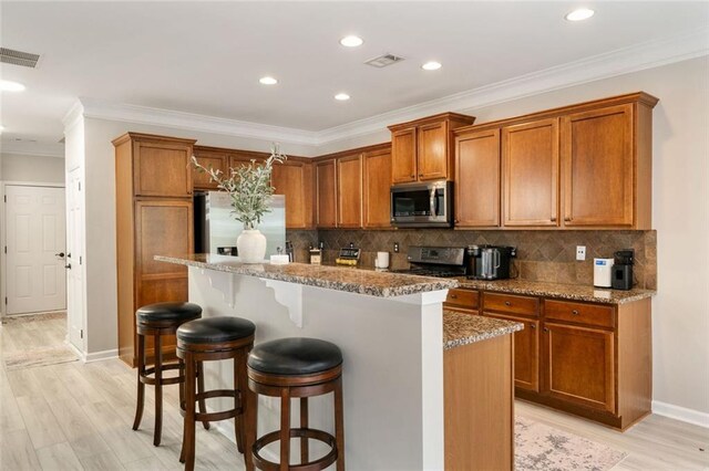 kitchen with visible vents, brown cabinetry, baseboards, a kitchen breakfast bar, and stainless steel appliances