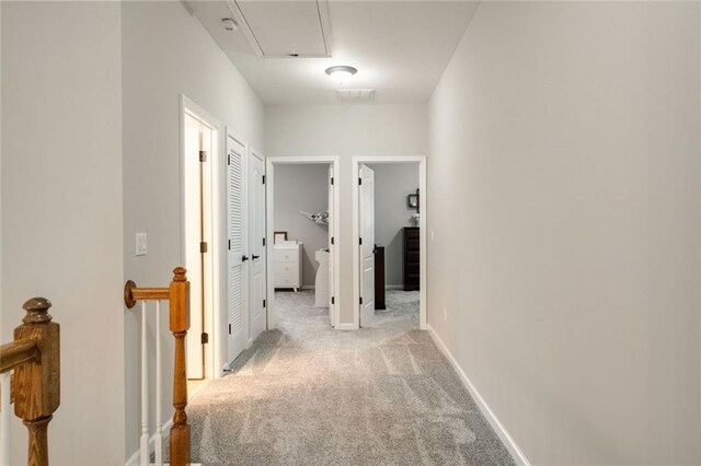 corridor featuring light carpet, attic access, baseboards, an upstairs landing, and visible vents