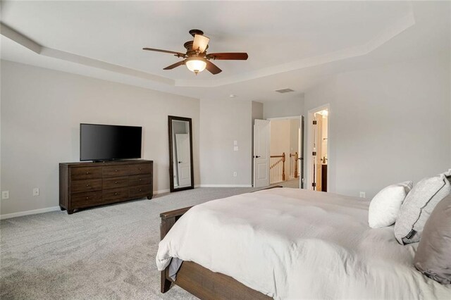 carpeted bedroom featuring baseboards, a ceiling fan, and a tray ceiling